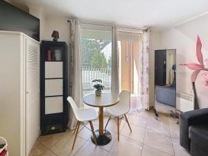 a living room with a table and chairs and a window at Direct Monaco Studio devant piscine in Beausoleil