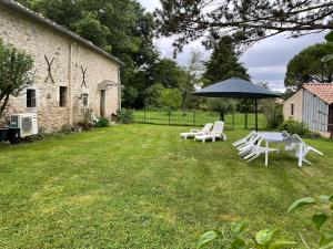 a table and chairs and an umbrella in a yard at La Tour du Sorbey - Gîte Nature Familial - Piscine - 3 à 6 Pax in Monségur
