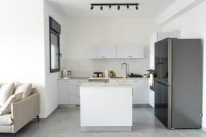 een witte keuken met een koelkast en een bank bij O&O Group Luxury Tower 4BR Panoramic Sea Views in Bat Yam