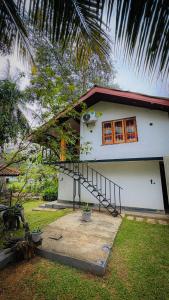 a white house with a staircase in front of it at Hotel Milenium in Kurundankulama