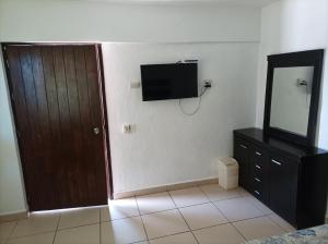 a room with a television and a door and a mirror at Habitación en Condominio frente al mar Nuevo Vallarta in Nuevo Vallarta