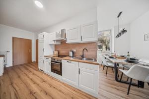 a kitchen with white cabinets and a dining table at Helle, gemütliche Wohnung in Zentrumsnähe in Magdeburg
