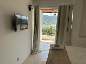 a bedroom with a bed and a tv and a window at Apartamentos com vista para o Mar - Mirante do Marinas in Angra dos Reis