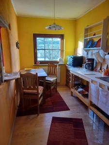a kitchen with yellow walls and a table and chairs at Wollwerkstatt Vulkaneifel in Borler