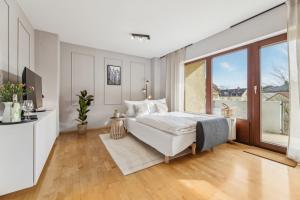 a white bedroom with a bed and a large window at Stay Malou Apartment zentrumsnah mit Kaffee-Teebar, Arbeitsplatz, Balkon und kostenlosen Stellplatz in Bayreuth