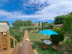 a wooden deck with a table and an umbrella at Le Chant des Tongs - Les Oliviers in Salazac
