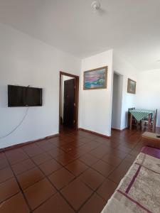 a living room with a tiled floor and a flat screen tv at Casa em Ubatuba 1 km do aquário in Ubatuba