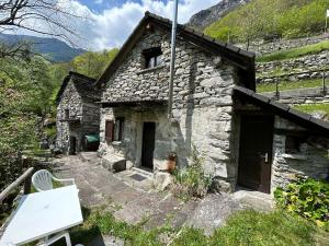 una vecchia casa in pietra con una panchina davanti di Rustic on the Verzasca River a Corippo