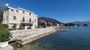a building sitting next to a body of water at Rooms Beba in Herceg-Novi