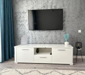 a white entertainment center with a television on a wall at Inga Apartment in Turda