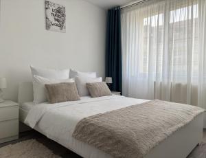 a white bedroom with a large bed and a window at Inga Apartment in Turda