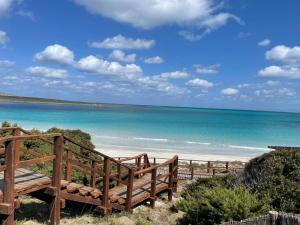 a wooden staircase leading to a beach with the ocean at Villetta Verde&Mare in Stintino