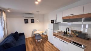 a living room with a blue couch and a kitchen at KukoriQ 1 Apartman in Siklós