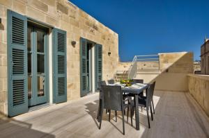 a patio with a table and chairs on a balcony at 10 Strait Street Apartments in Valletta