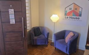 a room with two chairs and a lamp and a door at Le house hostel in São Paulo