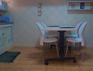 a table with four white chairs around it at Le house hostel in São Paulo