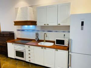 a kitchen with white cabinets and a sink and a refrigerator at A tu Vera in Ventas con Peña Aguilera