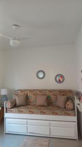 a white couch with two mirrors on the wall at Apartamento com Suíte em Bertioga Indaiá 150 metros da Praia in Bertioga