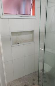a glass shower door with a window in a bathroom at Apartamento com Suíte em Bertioga Indaiá 150 metros da Praia in Bertioga