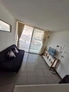 a living room with a black couch and a window at departamento pedro prado cercano al mall zofri in Iquique +10 photos