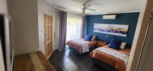 een kamer met twee bedden en een blauwe muur bij The Cozy Corner in Potchefstroom