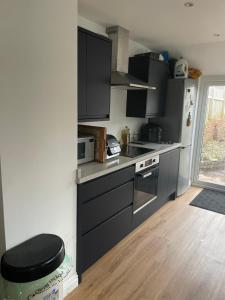 a kitchen with black cabinets and a stove top oven at Room close to City and Hospital in Cardiff