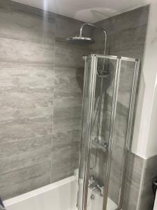a shower in a bathroom with a wooden wall at Room close to City and Hospital in Cardiff