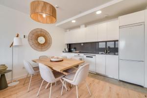 a kitchen with white cabinets and a wooden table and chairs at Sky Urban Tower in Málaga