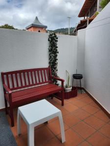 a red bench and a stool on a balcony at Santa Beatriz Apartment in Machico