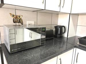 a microwave sitting on top of a counter in a kitchen at Sea Breeze Manor - Gold unit in East London +15 photos