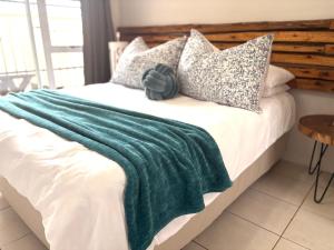 a bed with a green blanket and pillows on it at Sea Breeze Manor - Gold unit in East London