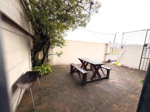 a picnic table and bench on a brick patio at Sea Breeze Manor - Gold unit in East London