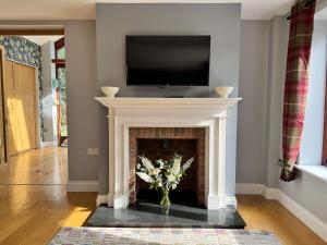 a living room with a fireplace with a tv above it at Little Luckford in Wareham