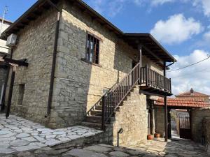 a stone house with a staircase on the side of it at En Kanalion well in Kanália