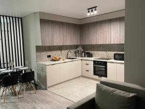 a kitchen with white cabinets and a table and a couch at Uzhhorod Apartment Lux in Uzhhorod