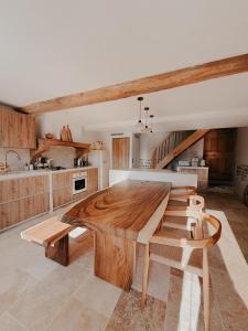 une grande cuisine avec une table et des chaises en bois dans l'établissement Charmante maison en pierres, séjour à la ferme, à Saint-Georges-dʼEspéranche