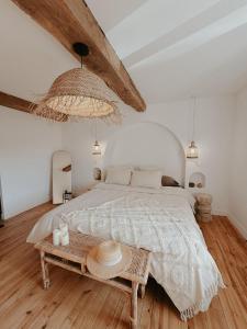 une chambre blanche avec un grand lit et une table dans l'établissement Charmante maison en pierres, séjour à la ferme, à Saint-Georges-dʼEspéranche
