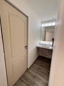 La salle de bains est pourvue d'une porte, d'un lavabo et d'un miroir. dans l'établissement Departamento Colonos Galeses, à Puerto Madryn