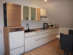 a kitchen with white cabinets and a sink at Deichblick Nordseeküste Bremerhaven in Imsum