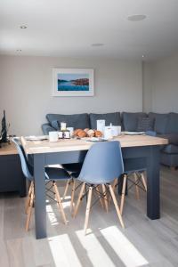 a dining room table with blue chairs and a table and a couch at Beach View - Stylish Stay, Estuary Views & Luxury Spa Access in Salcombe