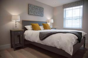 a bedroom with a bed with yellow pillows and a window at Beach View - Stylish Stay, Estuary Views & Luxury Spa Access in Salcombe +14 photos