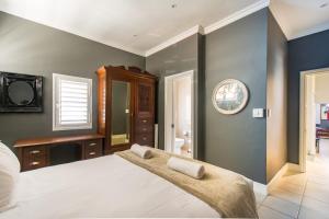 Un dormitorio con una cama grande y un espejo. en Millwood Apartment, en Ciudad del Cabo