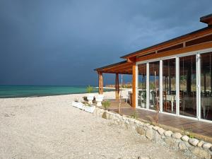 a building on a beach with the ocean behind it at Apartments Rezidenca Sinani Orikum in Orikum