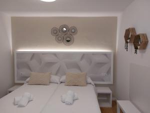 a bedroom with a white bed with two pillows at Pensión Cabezas in Lugones