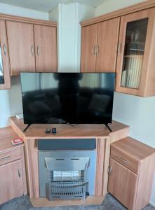 una grande TV a schermo piatto su un supporto in legno di L28 Millfield 4 Berth 3 Bedrooms DG & GCH Familys Only And Lead Person Must Be Over 30 a Ingoldmells