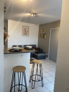 a kitchen with two bar stools and a living room at Le calme à proximité de la mer in Canet-en-Roussillon +7 photos