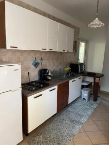 Una cocina con gabinetes blancos y una encimera negra. en Al giardino, en Taranto 7 fotos más
