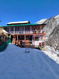 a house in the snow with a bench in front at Shivaay homestay,cafe in Tosh