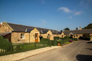 a row of stone houses with a fence on a street at Avocet Cottage in Lucker
