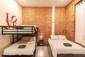 um quarto com 2 beliches e uma parede de tijolos em Studio Plus - Cozy Apartments em Nova Iorque